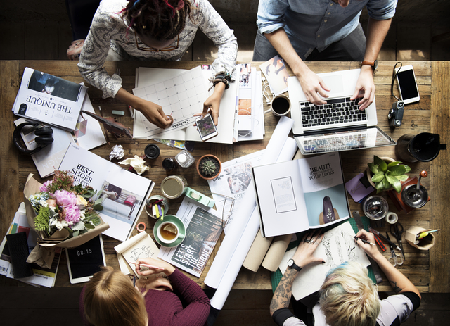 une table de 4 personnes avec différents éléments de communication (ordinateur, planning, téléphones...)